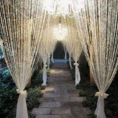 the walkway is lined with white lights and draping for an outdoor wedding ceremony