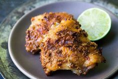 two pieces of chicken on a plate with a lime wedge