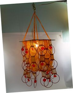 a chandelier hanging from the ceiling made out of paper circles and orange ribbons