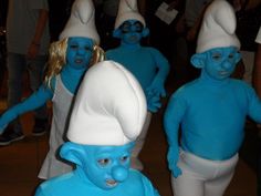 several people in blue and white costumes are walking around with their heads turned to look like smurfs