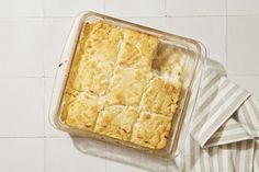 a casserole in a glass dish on top of a striped towel next to a white tiled wall