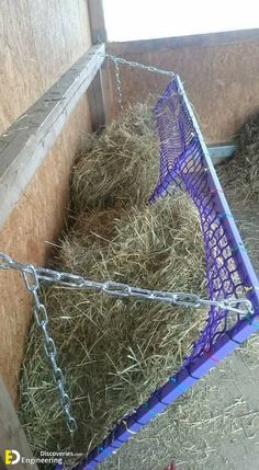 a purple cage with hay in it and chains hanging from the sides, on top of a pile of straw