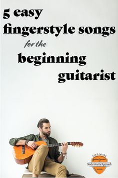 a man sitting on top of a chair holding a guitar in front of a white wall