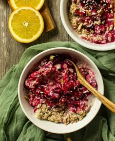 two bowls filled with cranberry oatmeal next to sliced oranges