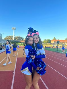 two cheerleaders hugging each other on a track