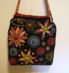 a handbag hanging on the wall with flowers and leaves painted on it's side