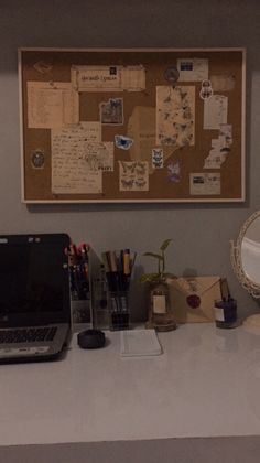 a laptop computer sitting on top of a desk next to a mirror and other office supplies