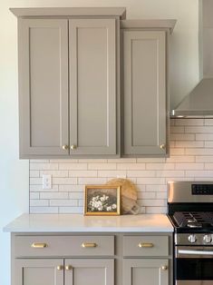 a kitchen with gray cabinets and white subway backsplash