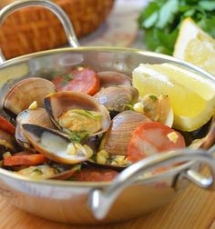 a pan filled with clams and vegetables on top of a wooden table