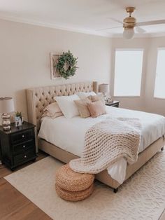 a bedroom with a large bed and two windows in the corner, along with a rug on the floor