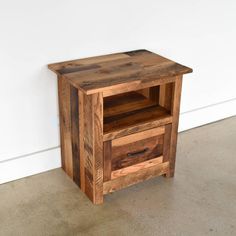 a small wooden table with two drawers on it's sides, against a white wall