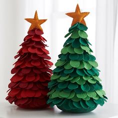 two paper christmas trees sitting on top of a white table next to eachother