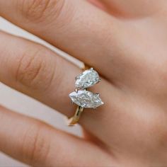 a woman's hand with a diamond ring on top of her finger and the other hand holding an engagement ring