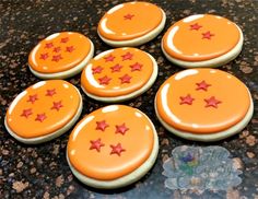 six decorated cookies sitting on top of a black counter next to a glass plate with red stars