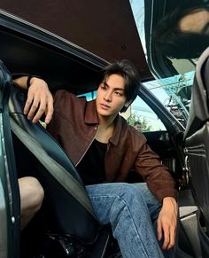 a man sitting in the passenger seat of a car with his hand on the door handle