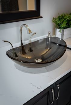 a bathroom sink sitting on top of a white counter next to a potted plant