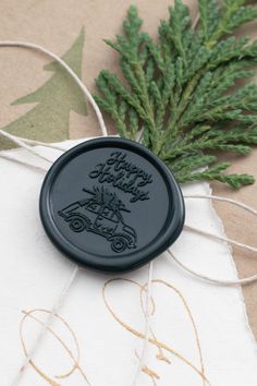 a waxy stamp with the words happy holidays on it sits next to some pine branches