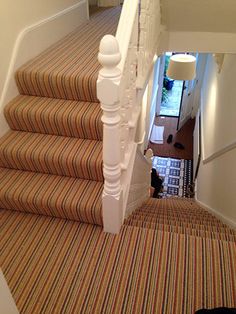 the stairs are lined with striped carpet and white railings