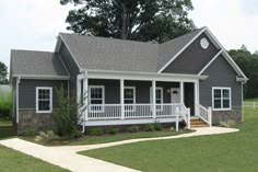 a gray house with white porches in the front yard and grass on the side