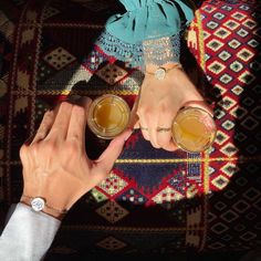 two people holding glasses with drinks in them on top of a carpeted area next to each other