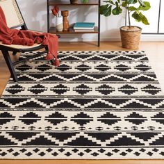 a black and white area rug with a chair next to it in front of a bookshelf