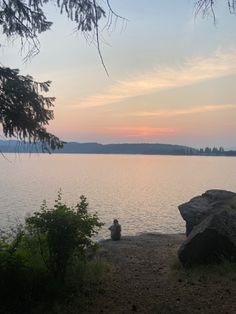 a person sitting on a rock near the water