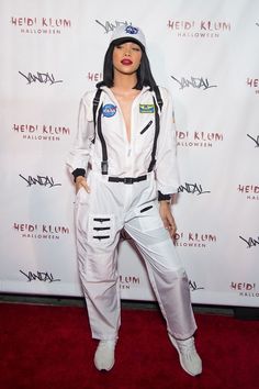 a woman in white jumpsuits standing on a red carpet with her hands behind her back