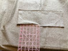 a close up of a piece of cloth with pink thread on it and a ruler in the middle