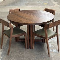 A round wooden dining table paired with matching chairs featuring green leather cushions, ideal for stylish and comfortable dining experiences. Modern Dining Table Design, Dining Table Design Modern, Round Pedestal Dining, Round Pedestal Dining Table, Pedestal Dining Table, Modern Dining Table