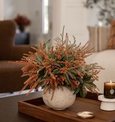 a table with a candle and some flowers on it in front of the couches