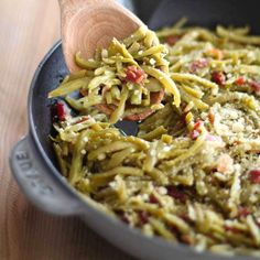 a wooden spoon scooping some food out of a pan