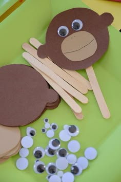 there is a paper plate with some stick and buttons on it that are shaped like a monkey