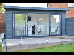 an outdoor living area with sliding glass doors and wooden decking in front of a brick building