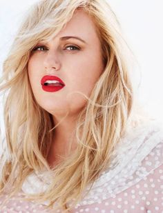 a woman with long blonde hair and red lipstick is posing for the camera while wearing a polka dot shirt