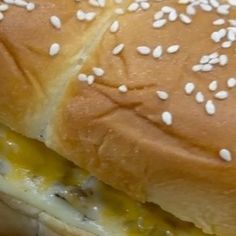 a close up of a sandwich with cheese and sesame seeds on it's bun