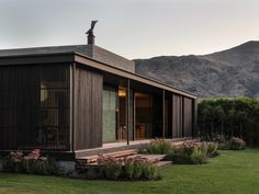 a small wooden house sitting in the middle of a lush green field with mountains in the background