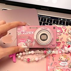 a pink camera sitting on top of a desk next to some stickers and other items