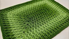 a green crocheted dishcloth sitting on top of a white table