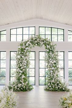 an indoor ceremony with white flowers and greenery