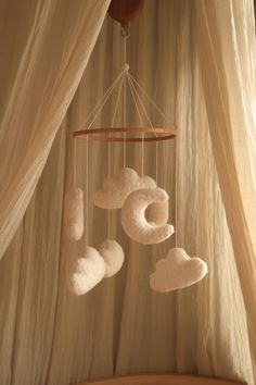 there is a white cloud mobile hanging from the ceiling in front of a drapes