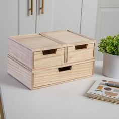 a wooden box sitting on top of a white table next to a potted plant