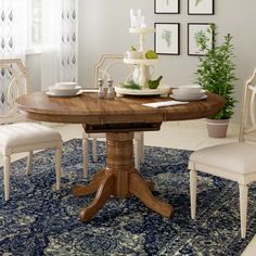 a dining room table with four chairs and a rug on the floor in front of it