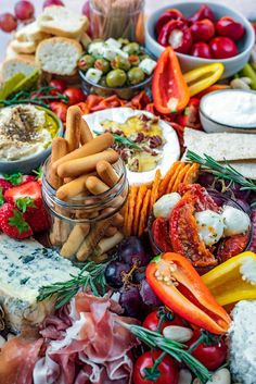 an assortment of food is displayed on a platter with cheese, crackers and tomatoes