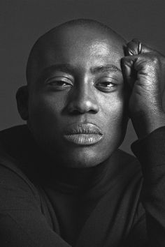 a black and white photo of a man with his hands on his head, looking at the camera