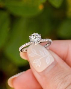 a close up of a person's hand holding a ring with a diamond on it