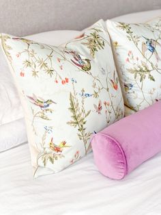 two pillows and a pink pillow on a bed