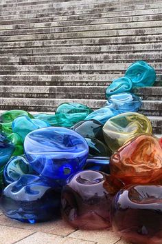 several colorful vases sitting on the ground in front of some steps