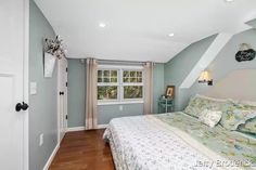 a bed sitting in a bedroom next to a window on top of a hard wood floor