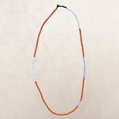 an orange and blue beaded necklace hangs from a string