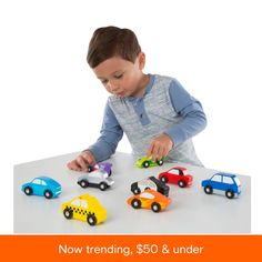 a young boy playing with toy cars on a table in front of white background,